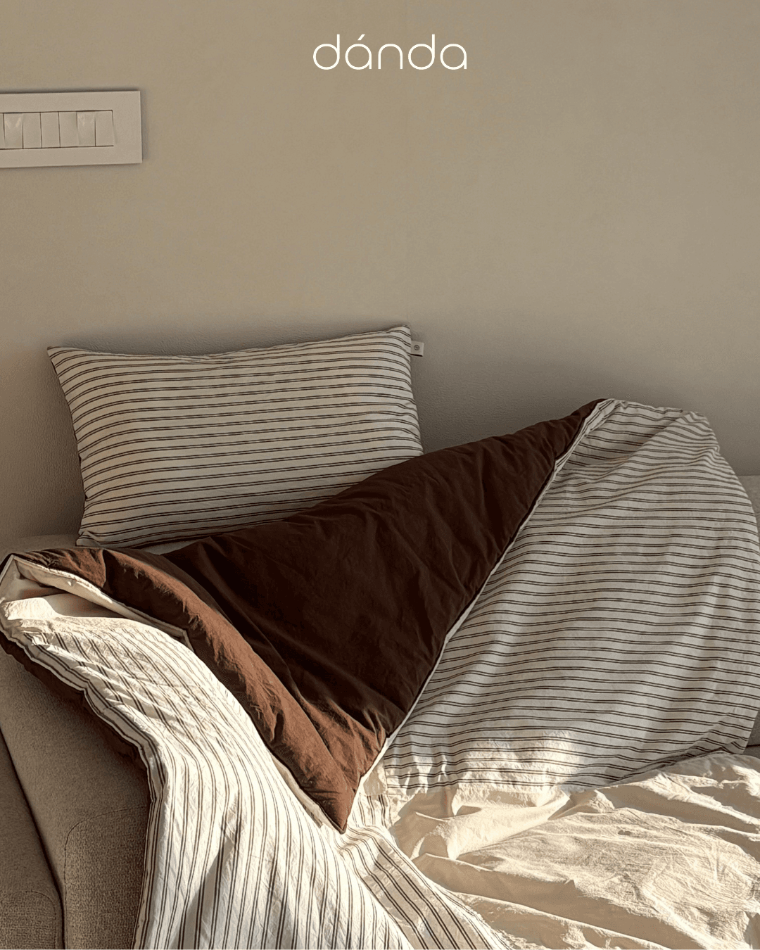 Soft nursery textiles and bedding arranged in a warm, lifestyle setting.